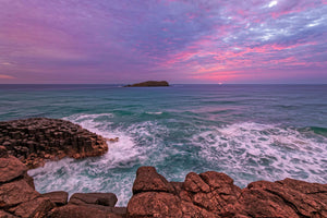 Landscape wall art of a pink sunrise over gentle ocean waves and rocky coast, titled The Sunrise Story, ideal for calming home and interior decor.