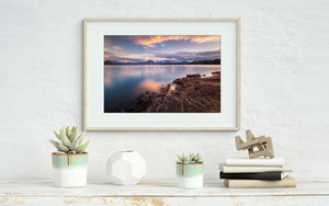 Lake sunrise photography wall art shown in a frame on a wall in home setting