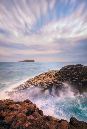 Ocean landscape wall art showing waves washing over basalt rocks under a soft pastel sky, captured in long exposure for home and interior décor.
